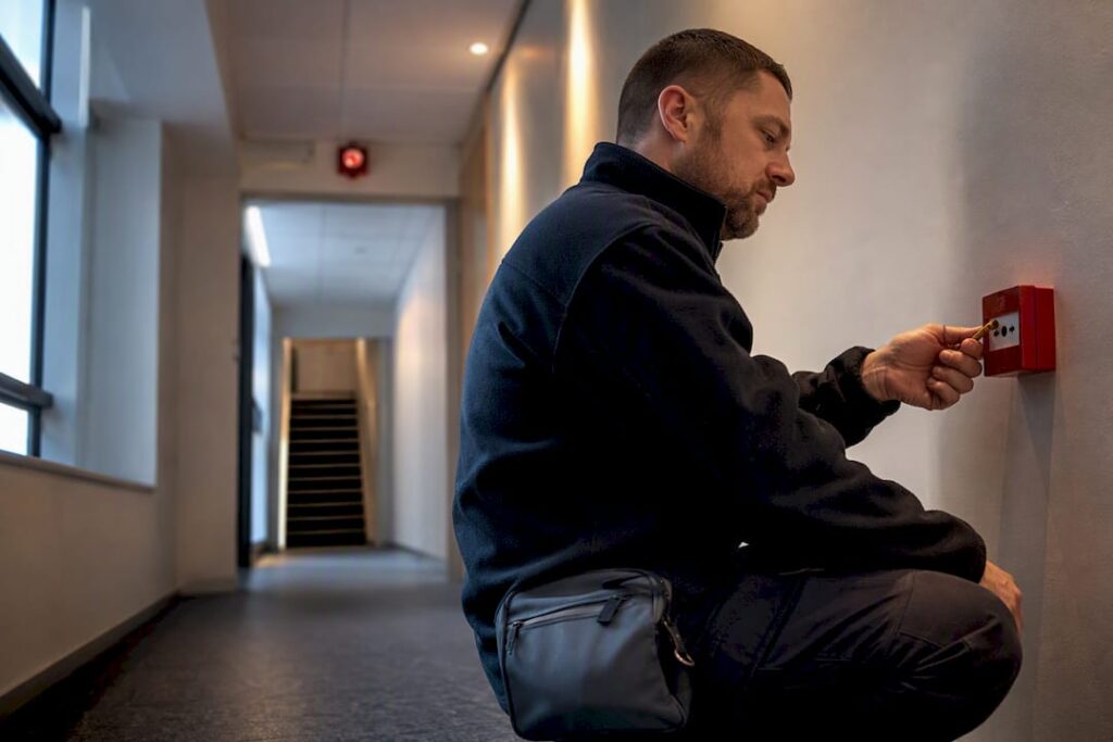 Technician testing a manual fire alarm call point